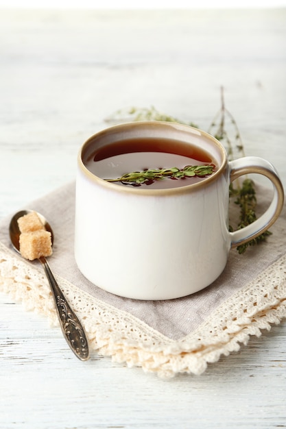 Taza de sabroso té de hierbas con tomillo en mesa de madera