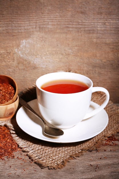 Taza de sabroso té rooibos en mesa de madera