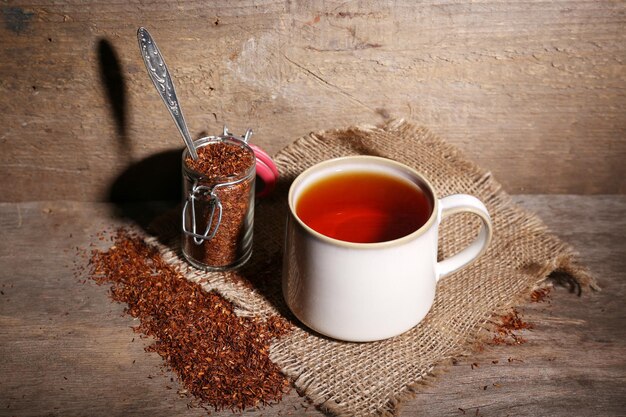 Taza de sabroso té rooibos en mesa de madera