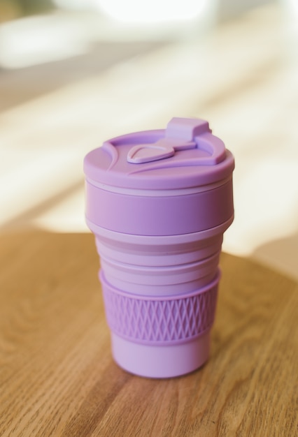 Taza de silicona plegable violeta para bebidas sin plástico al estilo de zero waste en una habitación interior, primer plano.