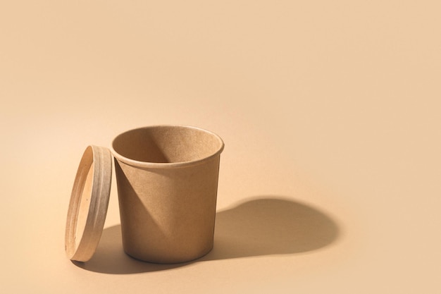 Taza de sopa de papel artesanal con sombra sobre fondo de papel marrón Recipiente vacío
