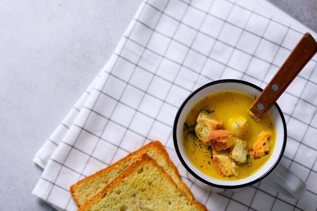 Taza de sopa de zanahoria de calabaza vegetariana cremosa de verduras con pan crachers en espacio de copia de fondo claro para su texto