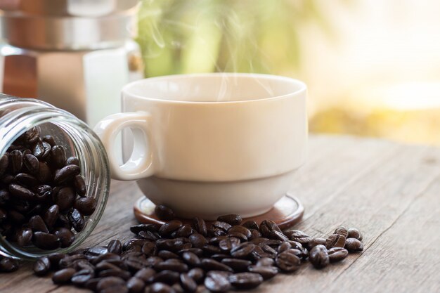 Una taza de taza de café exprés caliente y granos de café tostados