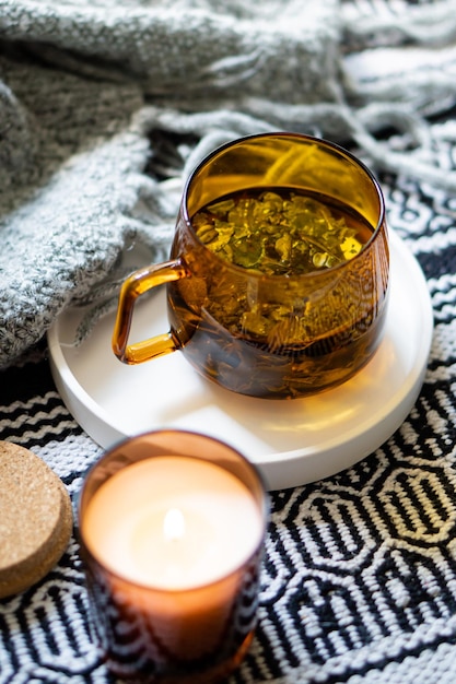 Taza de té y acogedora vela encendida en bandeja blanca