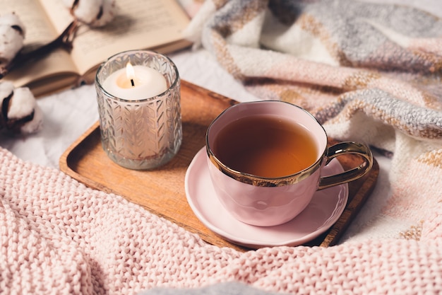 Taza de té, algodón, acogedor, libro, vela. Concepto acogedor de otoño invierno.