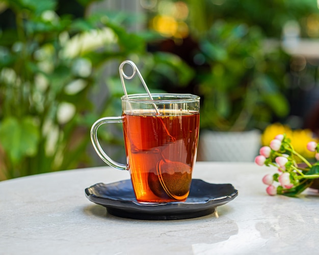 Taza de té aromático fresco en la mesa con la superficie de las flores de la naturaleza