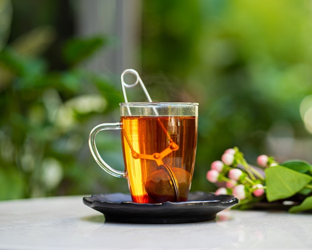 Taza de té aromático fresco en la mesa con la superficie de las flores de la naturaleza