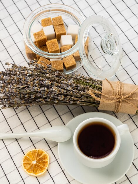 Una taza de té, azúcar, limón y un ramo de lavanda sobre una mesa