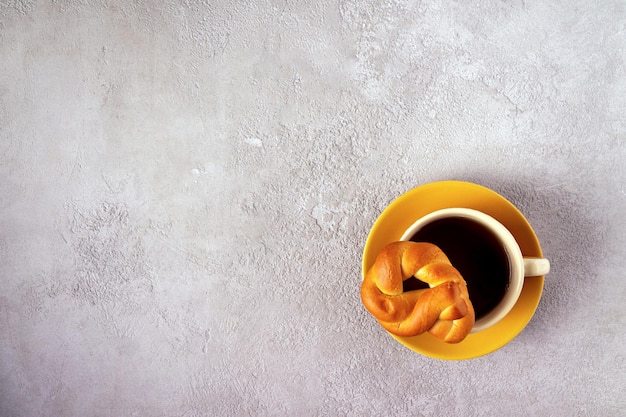 Una taza de té y un bagel en un espacio de copia de fondo gris