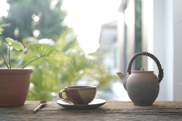 taza de té de barro y olla de té y olla de plantas en una mesa de madera al aire libre para relajarse bebiendo