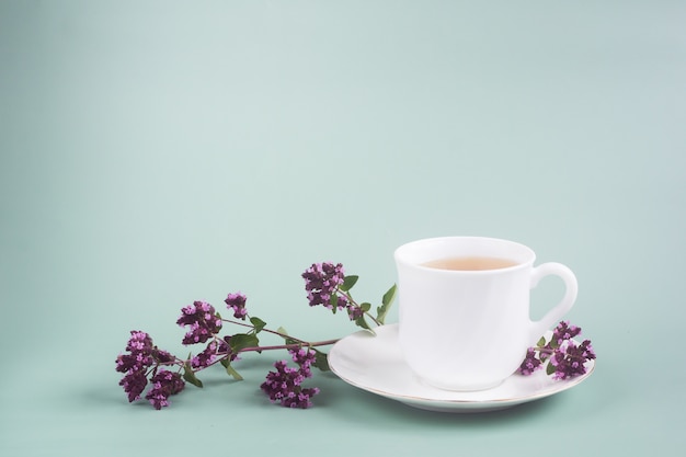 taza de té blanco con una ramita de orégano