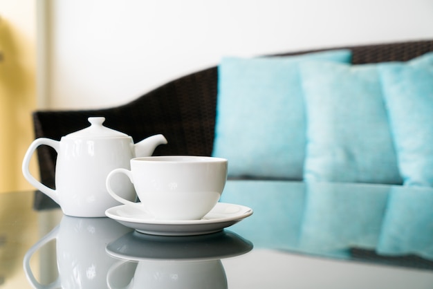 Taza de té blanco con tetera en la mesa en la terraza