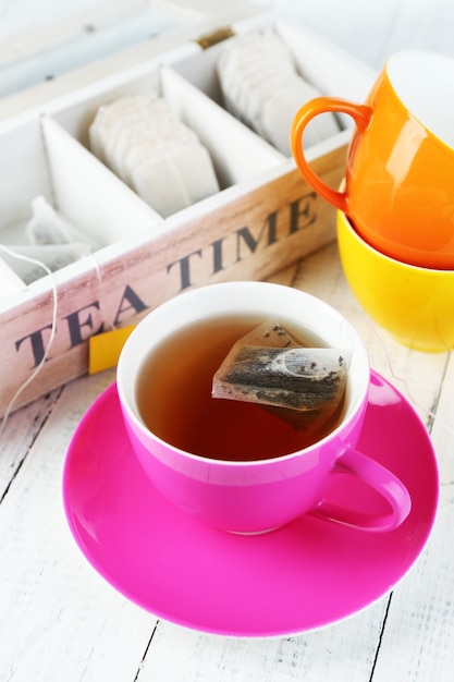 Foto taza con té y bolsitas de té en la mesa de madera