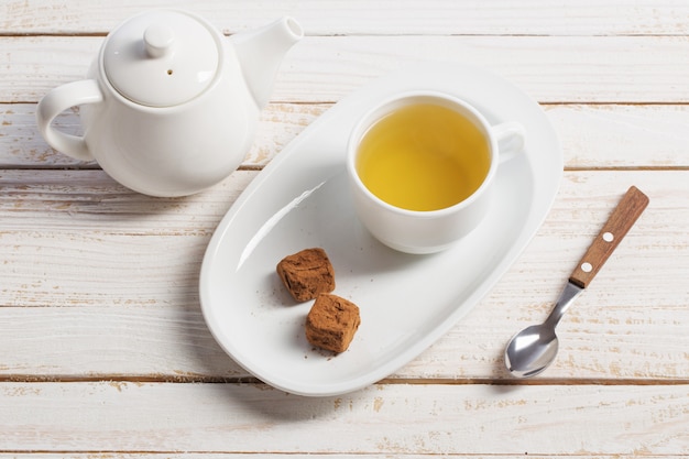 Taza de té con bombones en mesa de madera