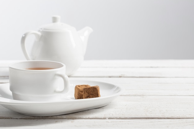 Foto taza de té con bombones en mesa de madera