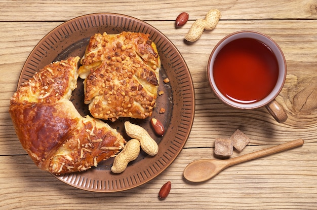 Taza de té caliente y bollos frescos con queso y nueces en la mesa de madera rústica, vista superior