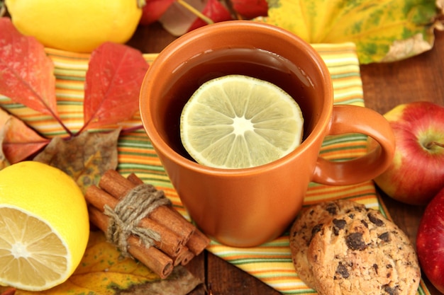 Una taza de té caliente y hojas de otoño en una mesa de madera