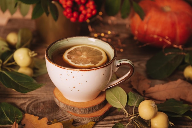 Una taza de té caliente con limón sobre un fondo de otoño Postal de otoño y otoño Día de Acción de Gracias o concepto de halloween