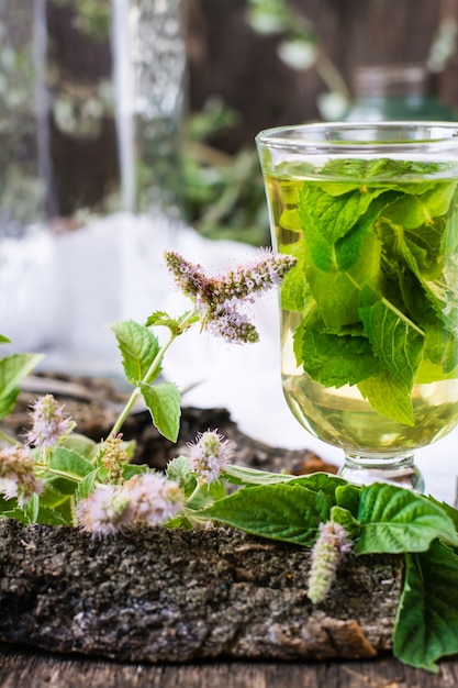 Una taza de té caliente con menta en una mesa de madera