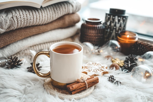 Una taza de té caliente y una pila de suéteres de punto en la foto estética del alféizar de la ventana