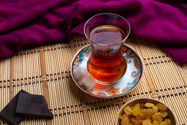 Una taza de té con chocolate negro oscuro y pasas.