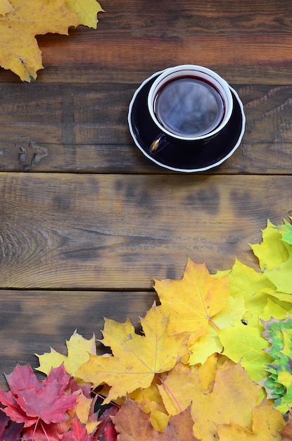 Una taza de té entre un conjunto de hojas de otoño caídas amarillentas