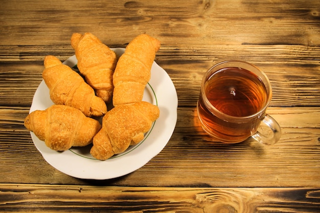 Taza de té y croissants en mesa de madera