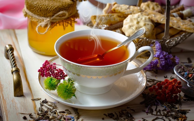 Foto una taza de té con una cuchara y un tarro de miel sobre la mesa.