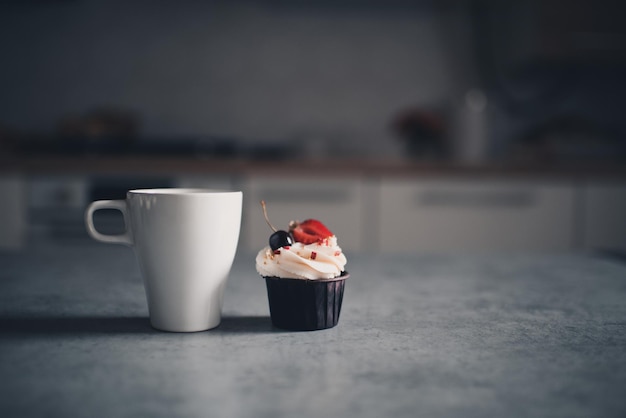 Taza de té con cupcake cremoso con frutos rojos