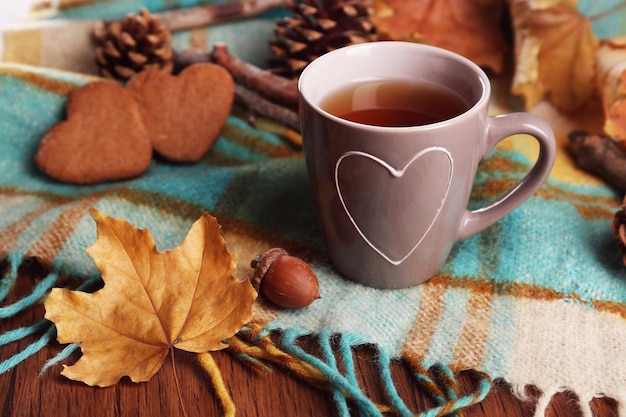 Taza de té con decoración de otoño en mesa de madera