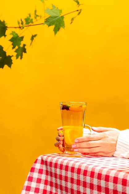 Taza de té con delicioso té dulce con cítricos, limones, jengibre, miel y una rodaja de mango aislada sobre amarillo