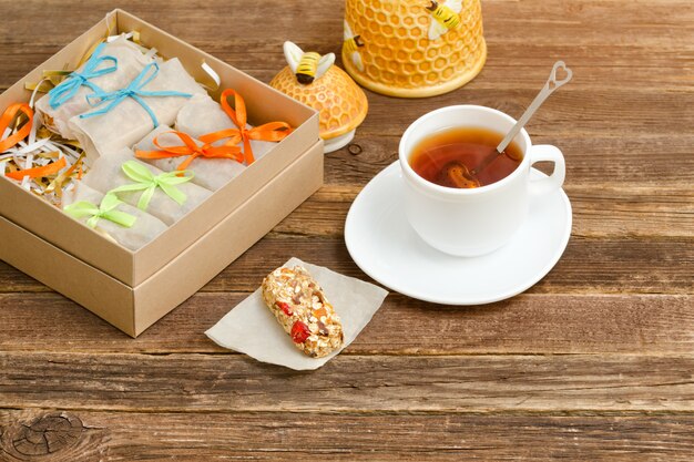 Taza de té, embalaje de barras y azucarero. Mesa de madera