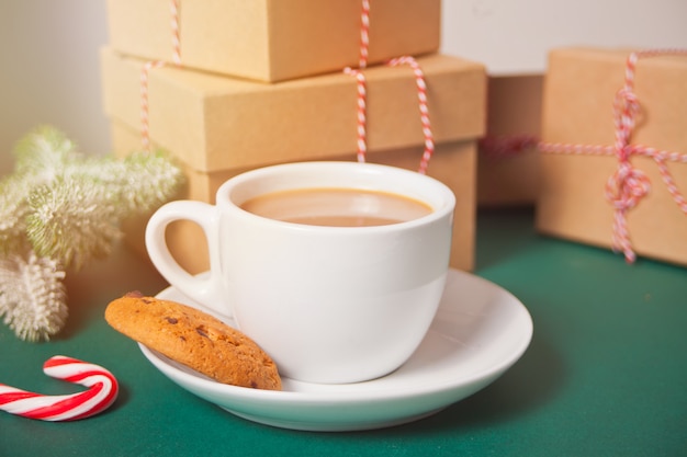 Taza de té, galleta casera, cajas de regalo de Navidad y decoración navideña.