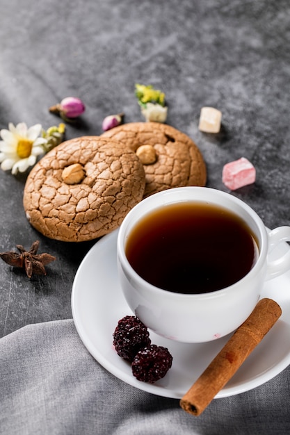 Una taza de té, galletas de almendras, bayas, canela y nueces.