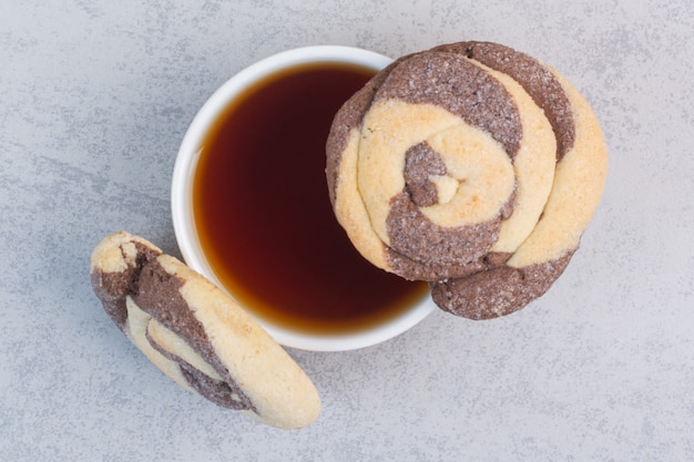 Una taza de té y galletas dulces, sobre el mármol.