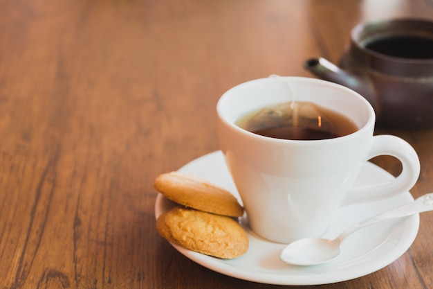 Una taza de té con las galletas en espacio de madera de la tabla y de la copia.