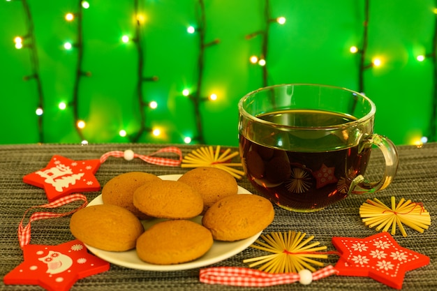 Una taza de té con galletas en el fondo de una guirnalda.