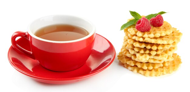 Taza de té con galletas y frambuesas aislado en blanco