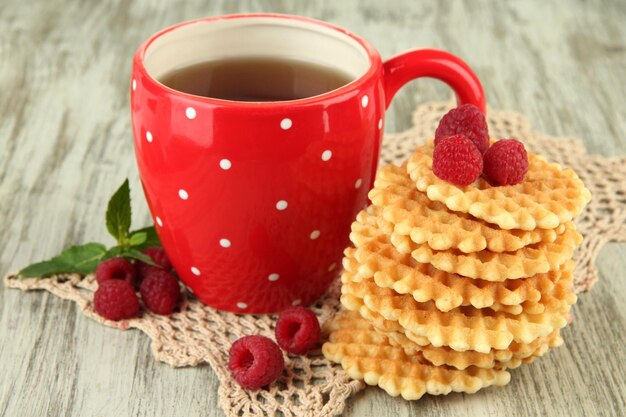 Taza de té con galletas y frambuesas en primer plano de la mesa