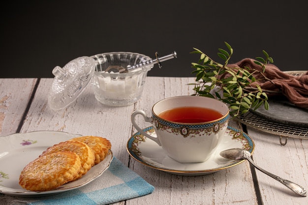 Taza de té con galletas en una mesa de madera blanca