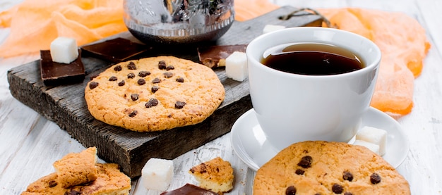 Taza de té, galletas en la mesa de madera blanca