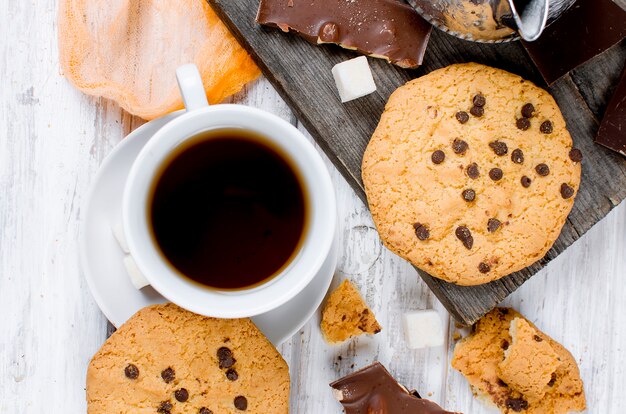 Taza de té, galletas en la mesa de madera blanca