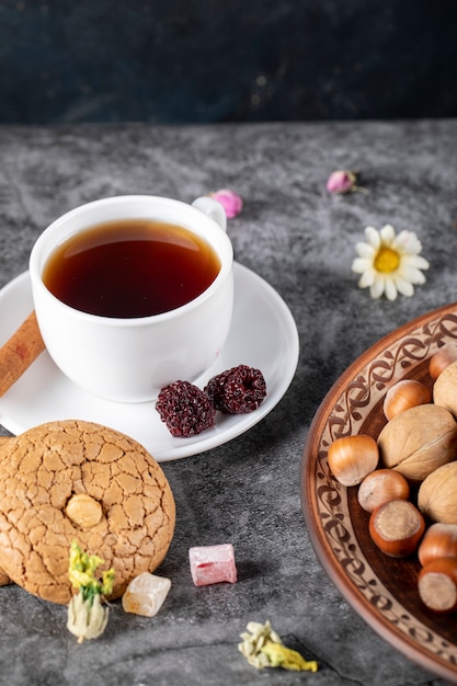 Una taza de té con galletas y nueces sobre la mesa