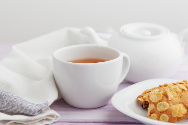 Taza de té con galletas sobre fondo de madera lila