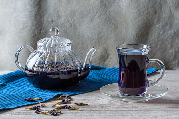 Una taza de té de guisante caliente Mariposa (flores de guisante, guisantes azules) para bajar de peso, desintoxicarse en una mesa de madera gris