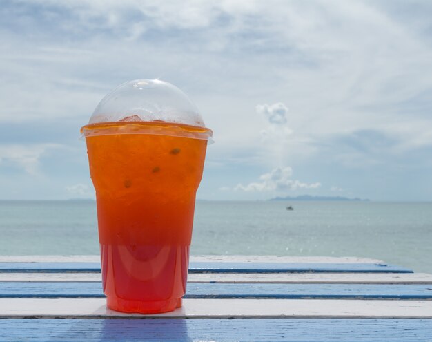 Foto taza de té helado en mesa blanca en mesa de madera en la playa