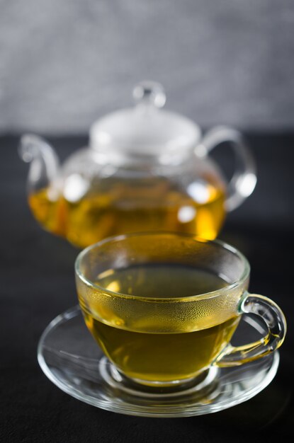 Taza de té de hierbas delicioso y tetera de vidrio.