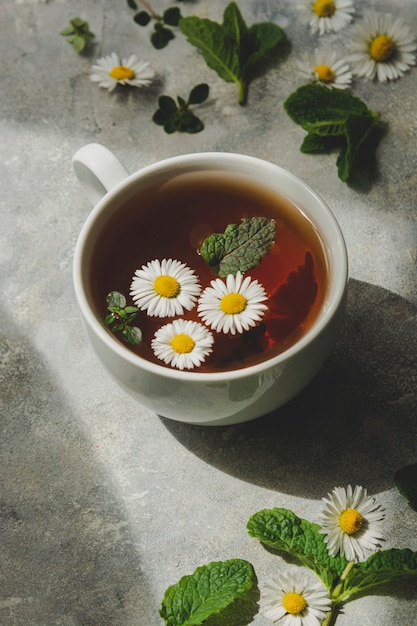 Taza de té de hierbas con flores de manzanilla y hojas de menta, espacio de copia