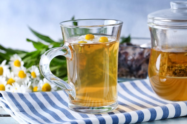 Taza de té de hierbas con flores de manzanilla en la mesa