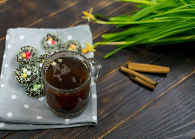 Una taza con té de hierbas y galletas sobre un fondo oscuro